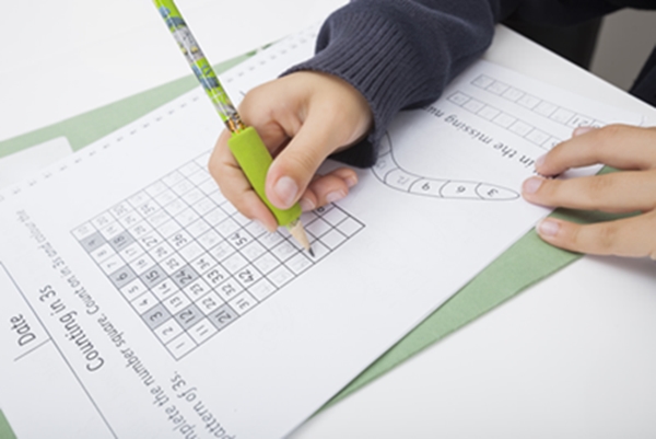 Close-up of girl's hand writing numbers on paper